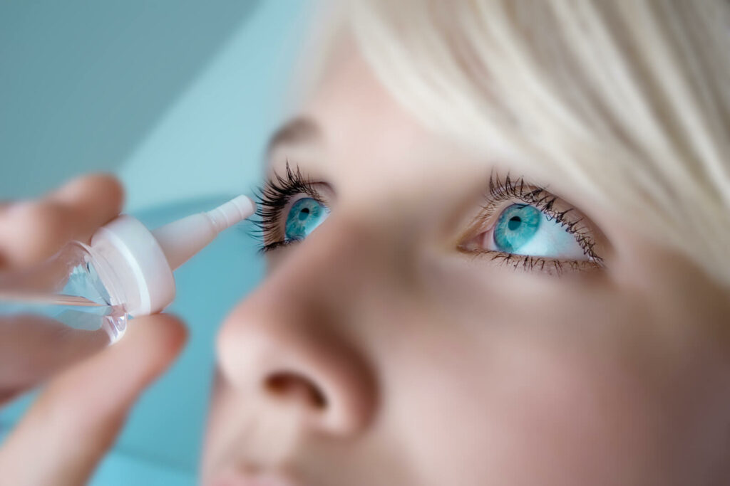 Woman putting eye drops in eye