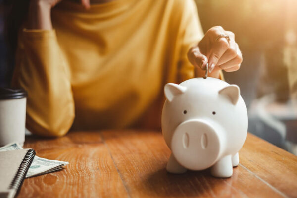Woman putting a coin in a white piggy bank