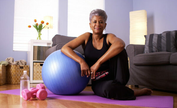 Senior woman on yoga mat with exercise ball and hand weights