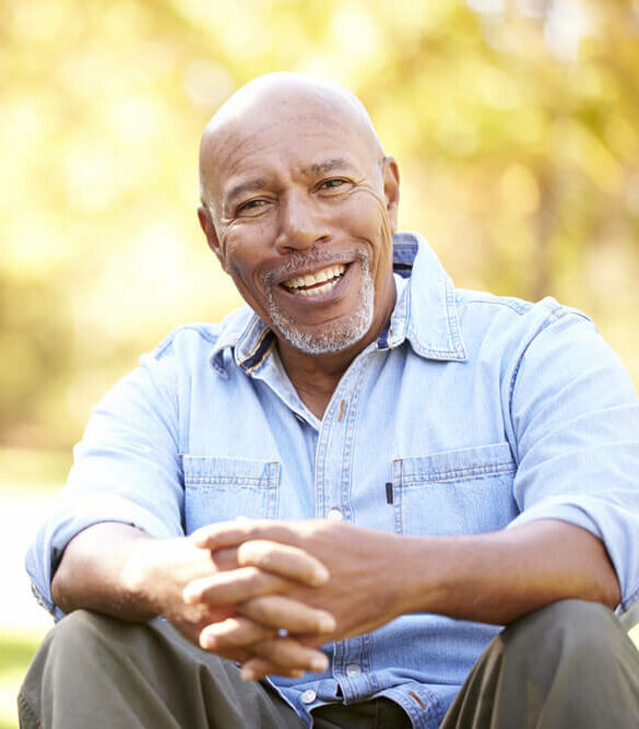 Senior man smiling at camera sitting outdoors