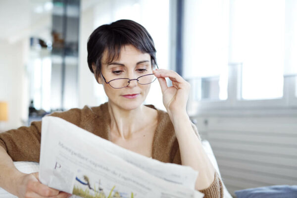 Woman wearing glasses reading newspaper